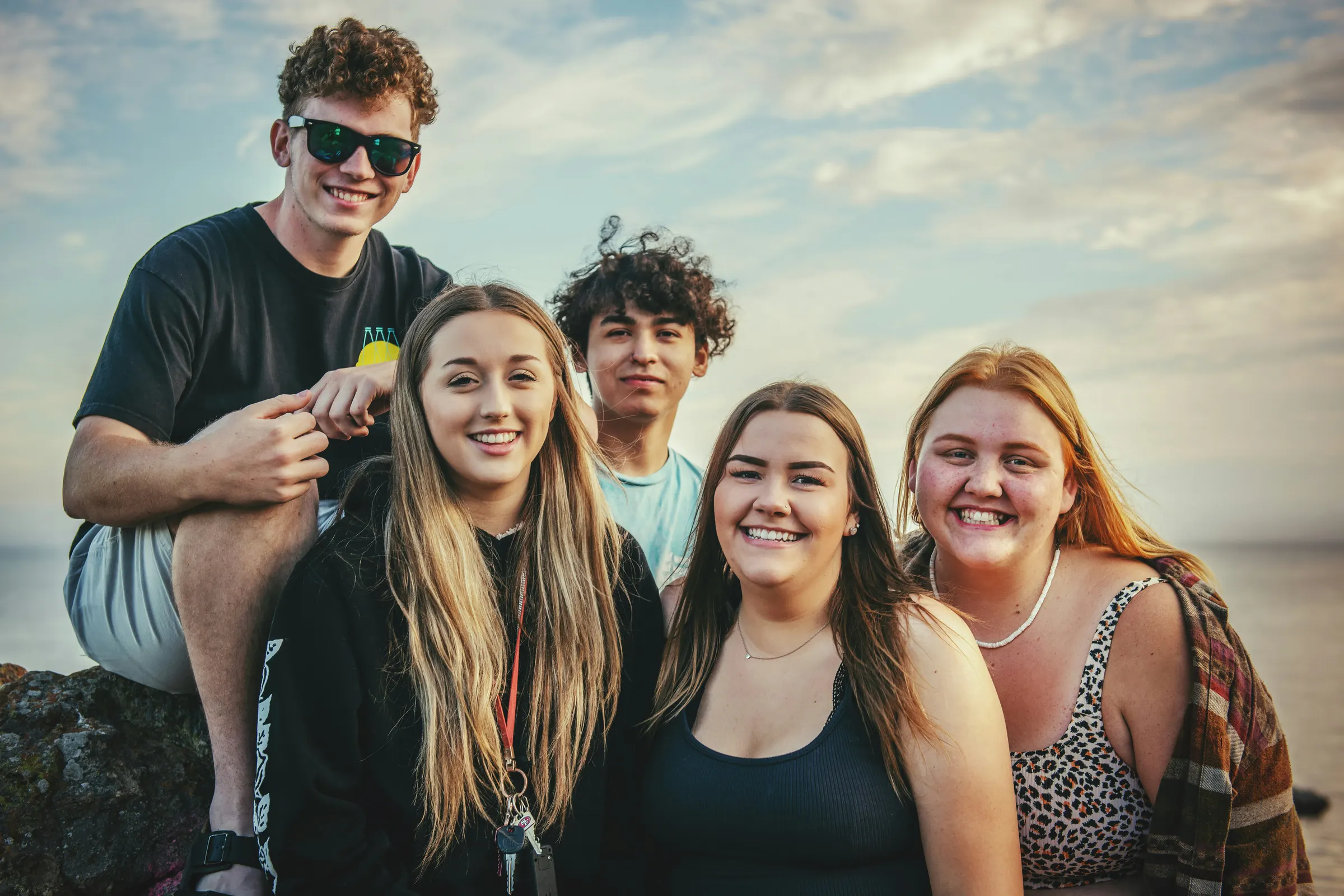 A group of friends smiling together by the sea